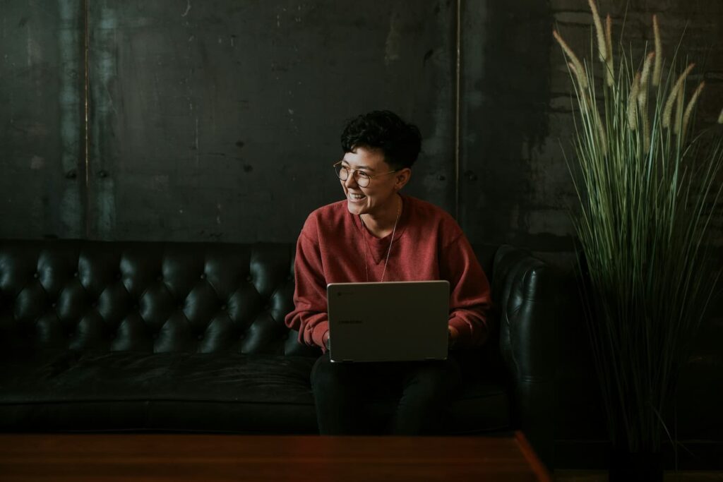 smiling-person-using-laptop-computer-while-sitting-on-black-leather-sofa
