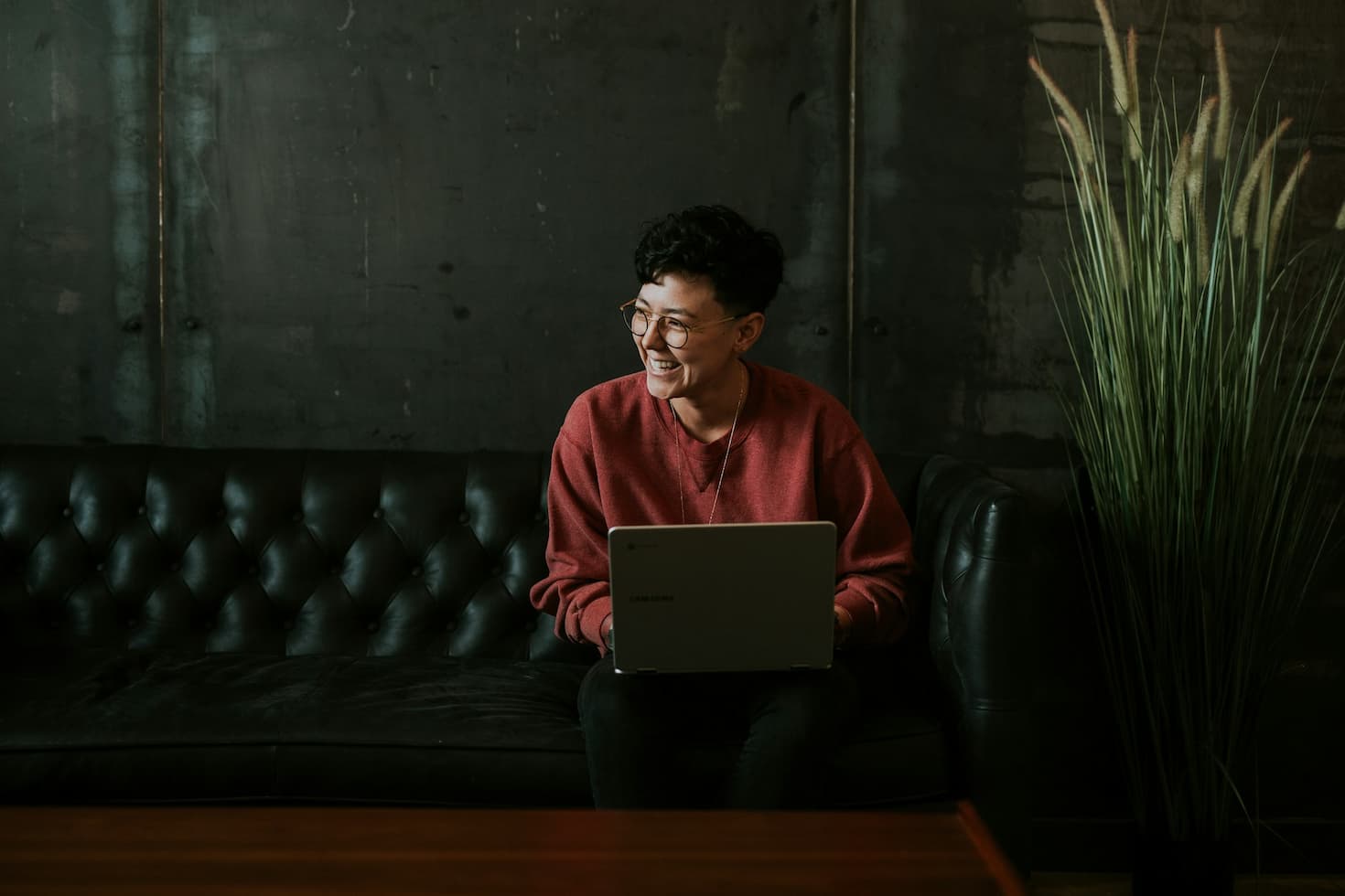 smiling-person-using-laptop-computer-while-sitting-on-black-leather-sofa