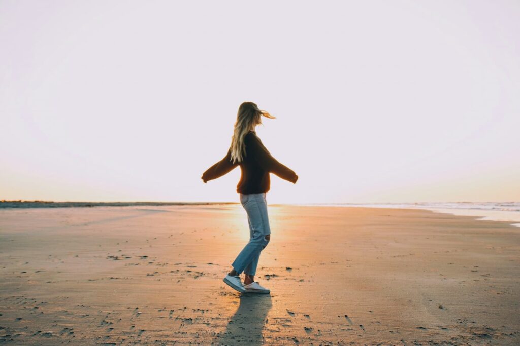 woman-standing-on-sand-near-seashore-during-golden-hour