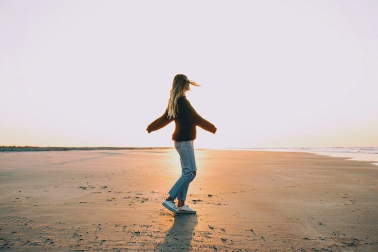 woman-standing-on-sand-near-seashore-during-golden-hour