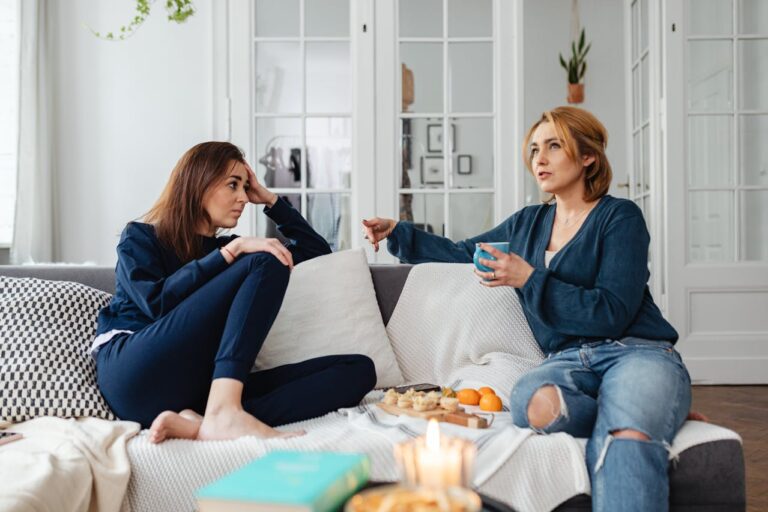 two-women-sitting-while-talking-on-a-sofa