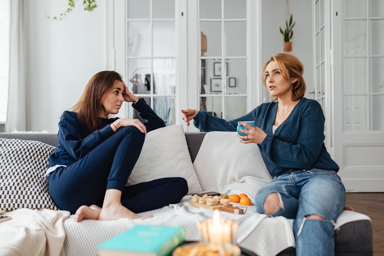 two-women-sitting-while-talking-on-a-sofa