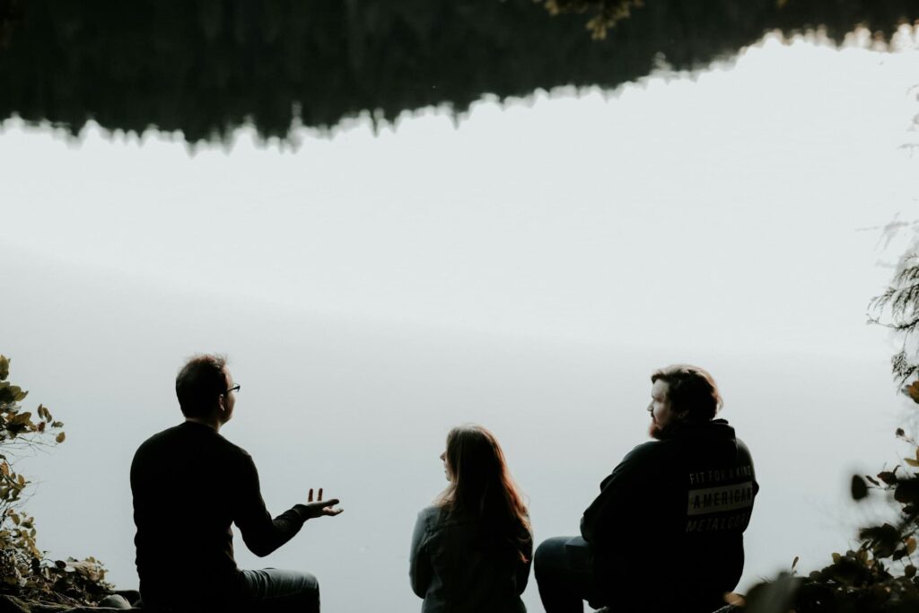 silhouette-of-three-people-sitting-on-cliff-under-foggy-weather
