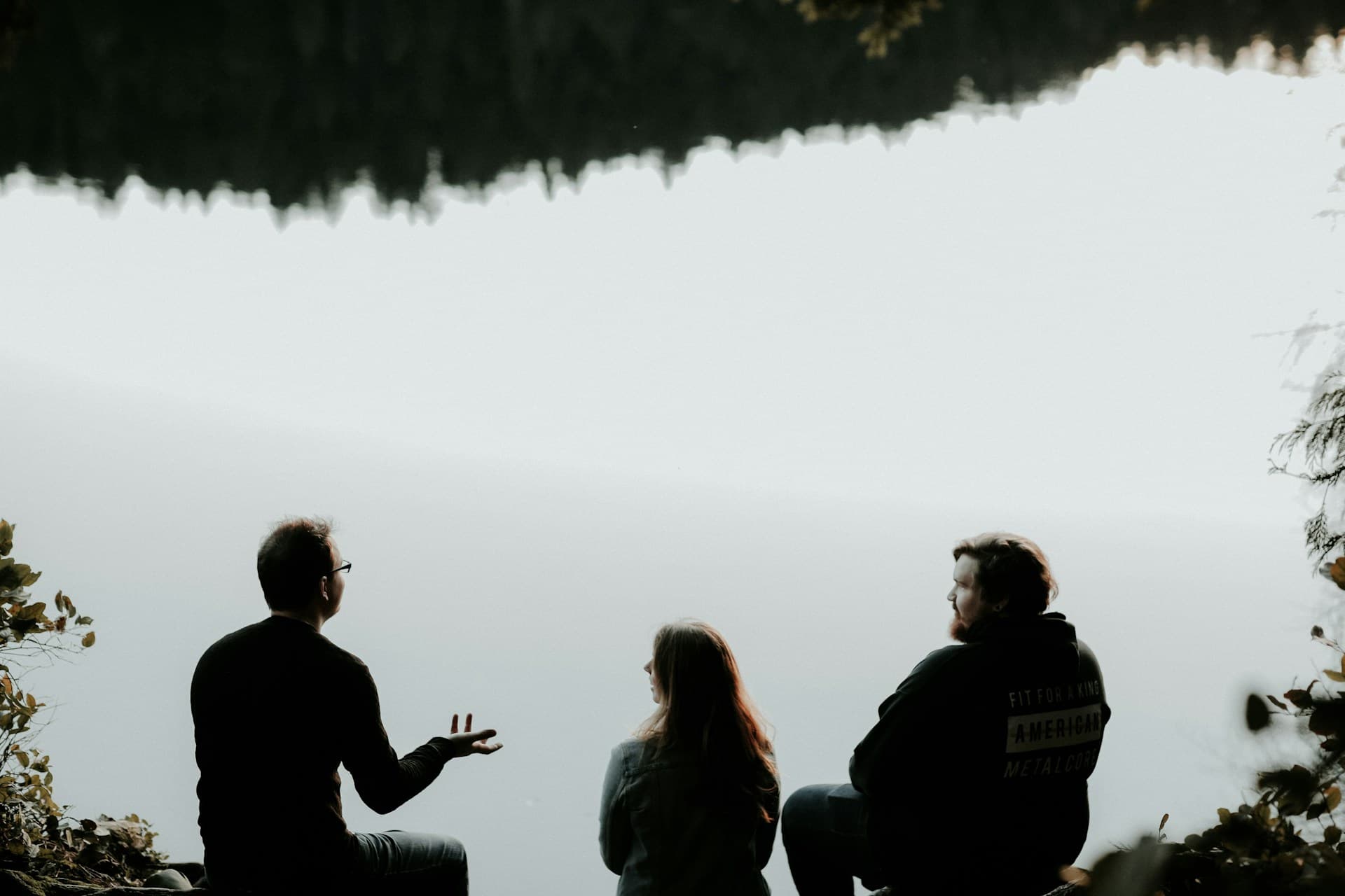 silhouette-of-three-people-sitting-on-cliff-under-foggy-weather