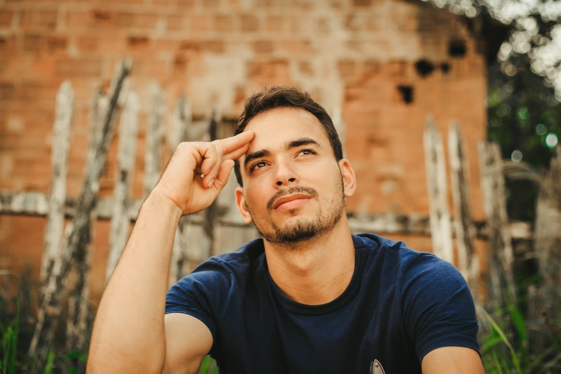 a-man-in-blue-shirt-looking-up-with-his-hand-on-his-head