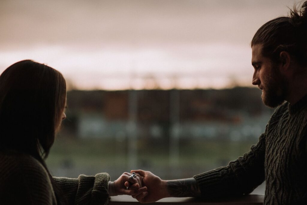 crop-couple-holding-hands-on-balcony-at-sunset