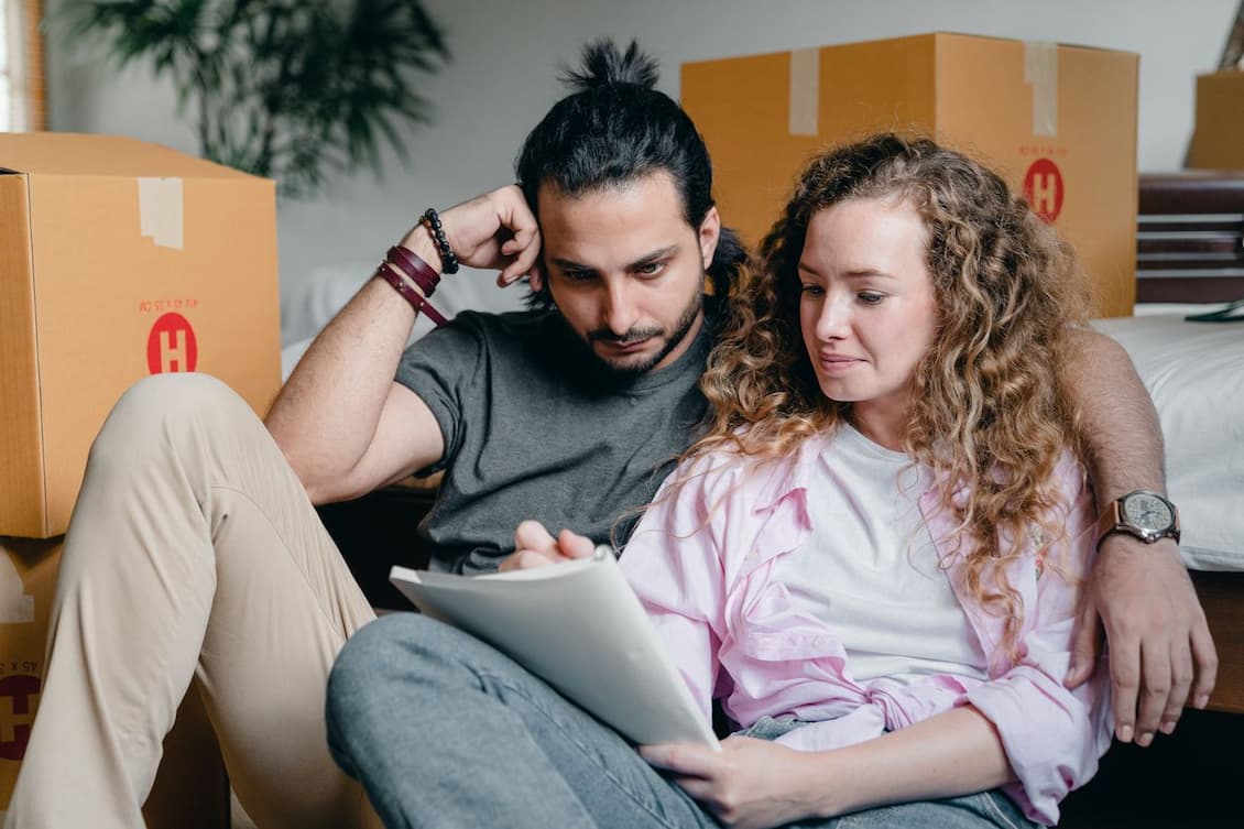 thoughtful-couple-writing-in-notebook-while-moving-house