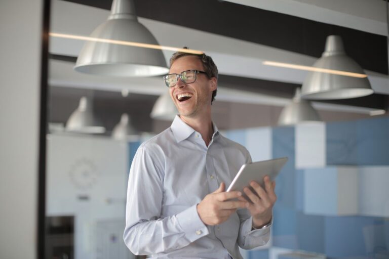 photo-of-laughing-man-in-white-dress-shirt-carrying-a-tablet