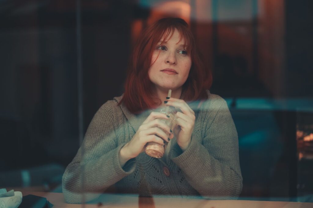redheaded-woman-behind-window-pane-drinking-juice