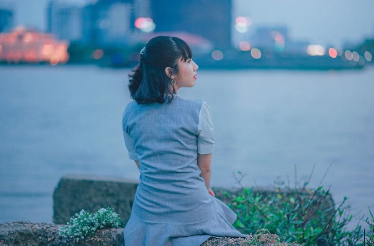 woman-wearing-gray-dress-sitting-near-body-of-water