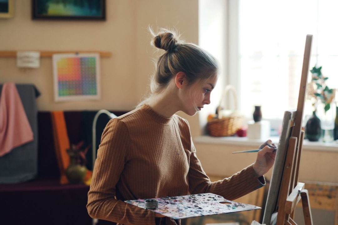 young-woman-painting-in-sunlit-art-studio